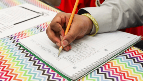 close up of student writing in a notebook