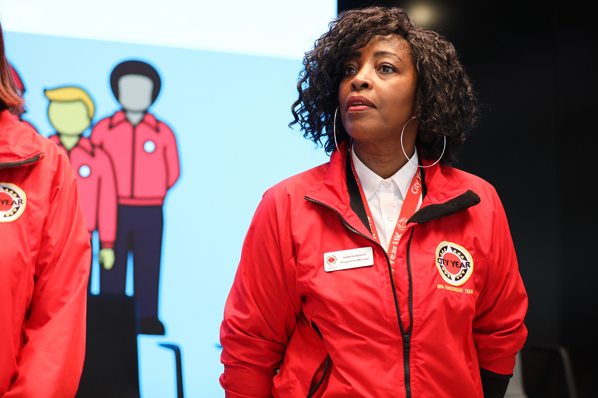 Staff member Sharon Webley in a red jacket speaking