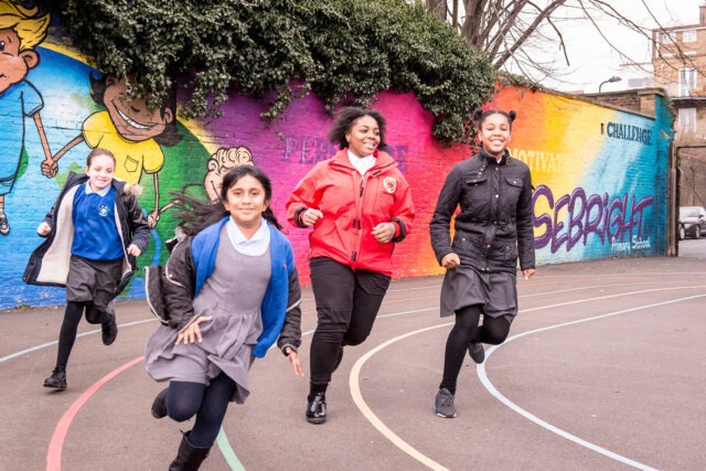 Volunteer mentor racing on a track with pupils