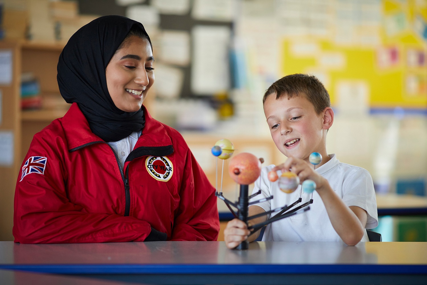 Female volunteer mentor in a hijab working with a pupil on a science project