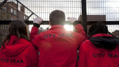 Volunteer mentors looking out, holding onto a fence