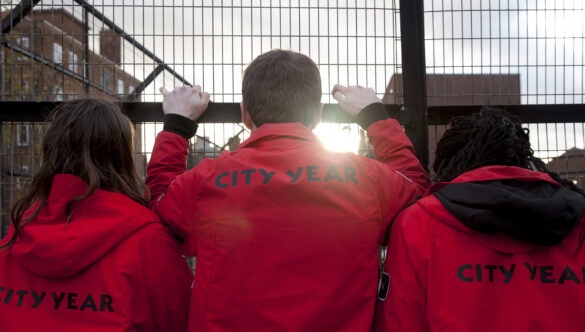 Volunteer mentors looking out, holding onto a fence