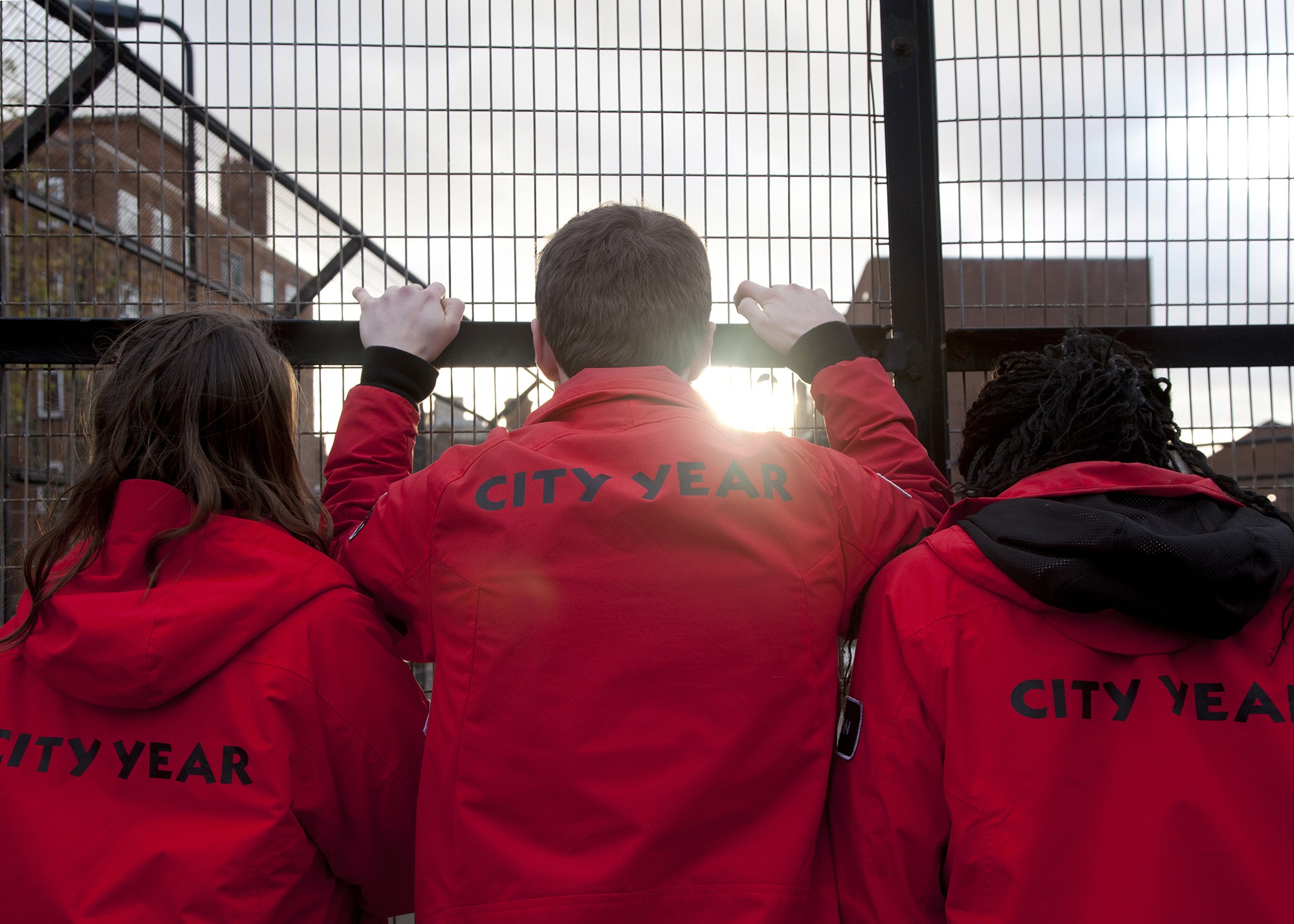 Volunteer mentors looking out, holding onto a fence