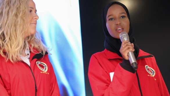 Two volunteer mentors on stage, one is holding a microphone and speaking