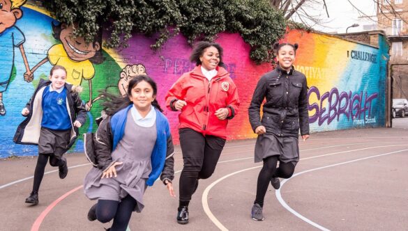 Volunteer mentor racing on a track with pupils