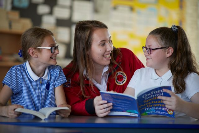 female volunteer interacting with two pupils at Mossfield school in Manchester